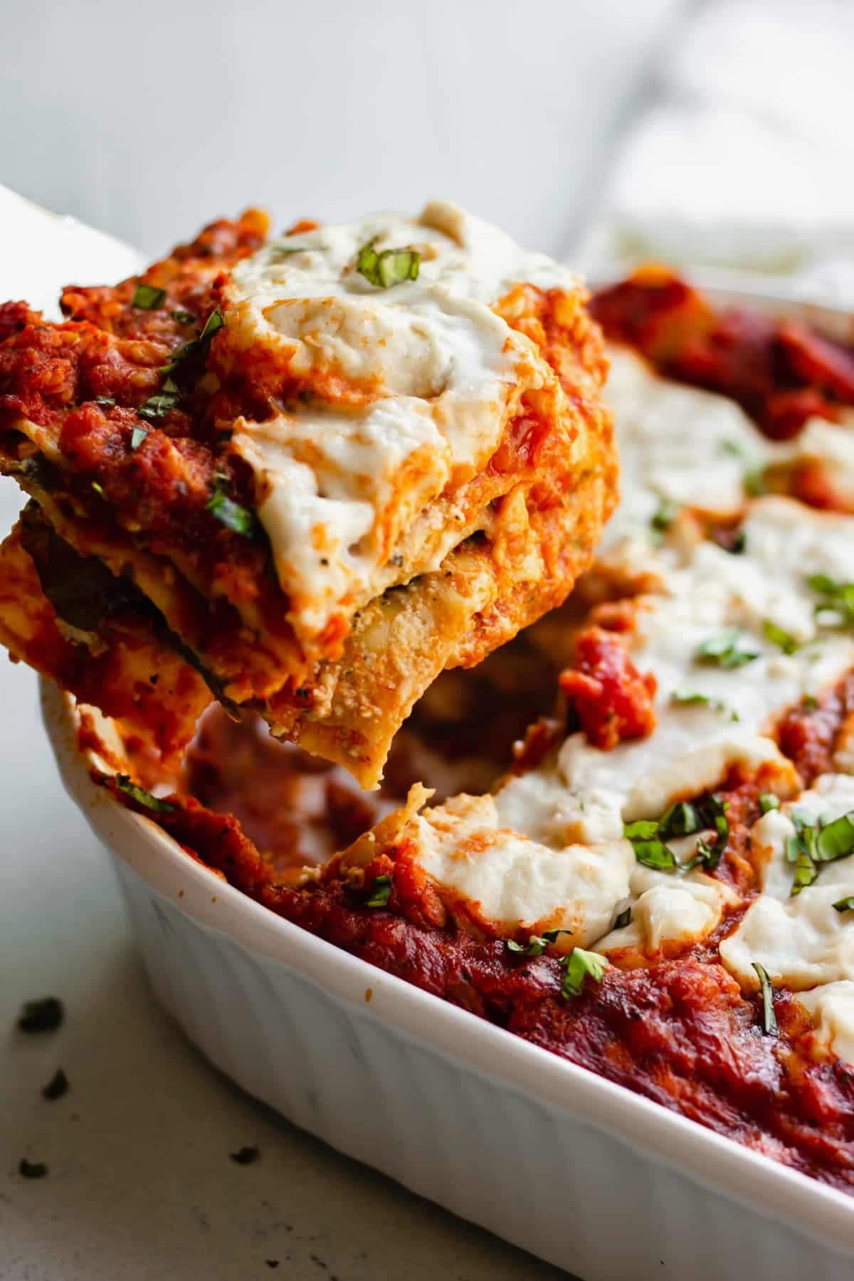 A slice of cheese layered lasagna from a casserole dish.