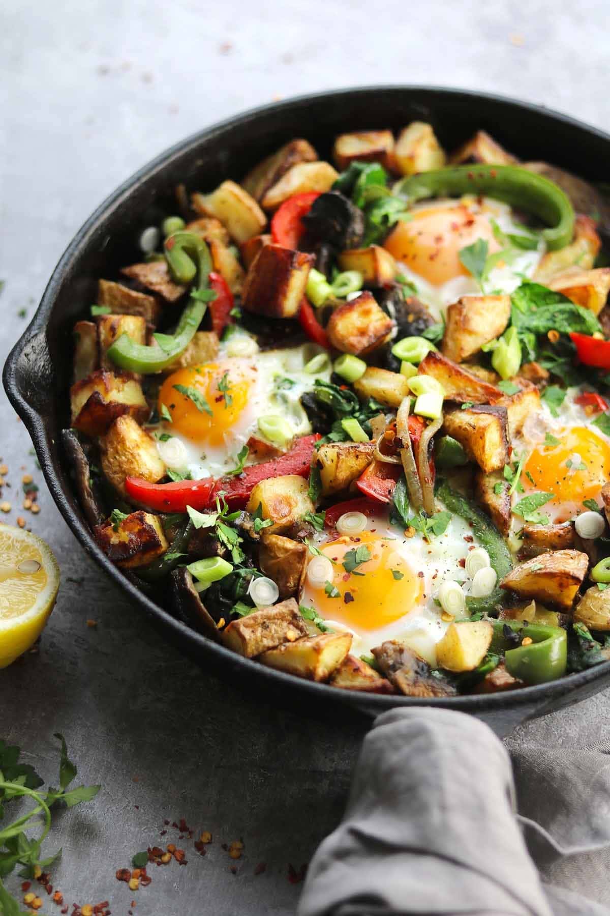 A skillet with a delicious mix of eggs, potatoes, bell peppers, mushrooms, oregano, spinach, green onions and chopped parsley