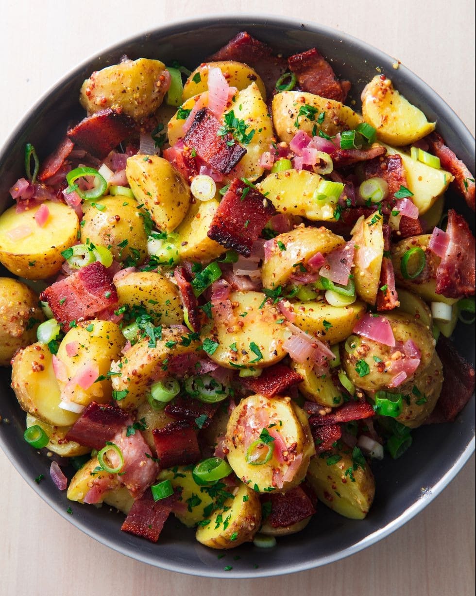 Potato salad with chopped bacon and green onions served in a bowl with bacon vinaigrette