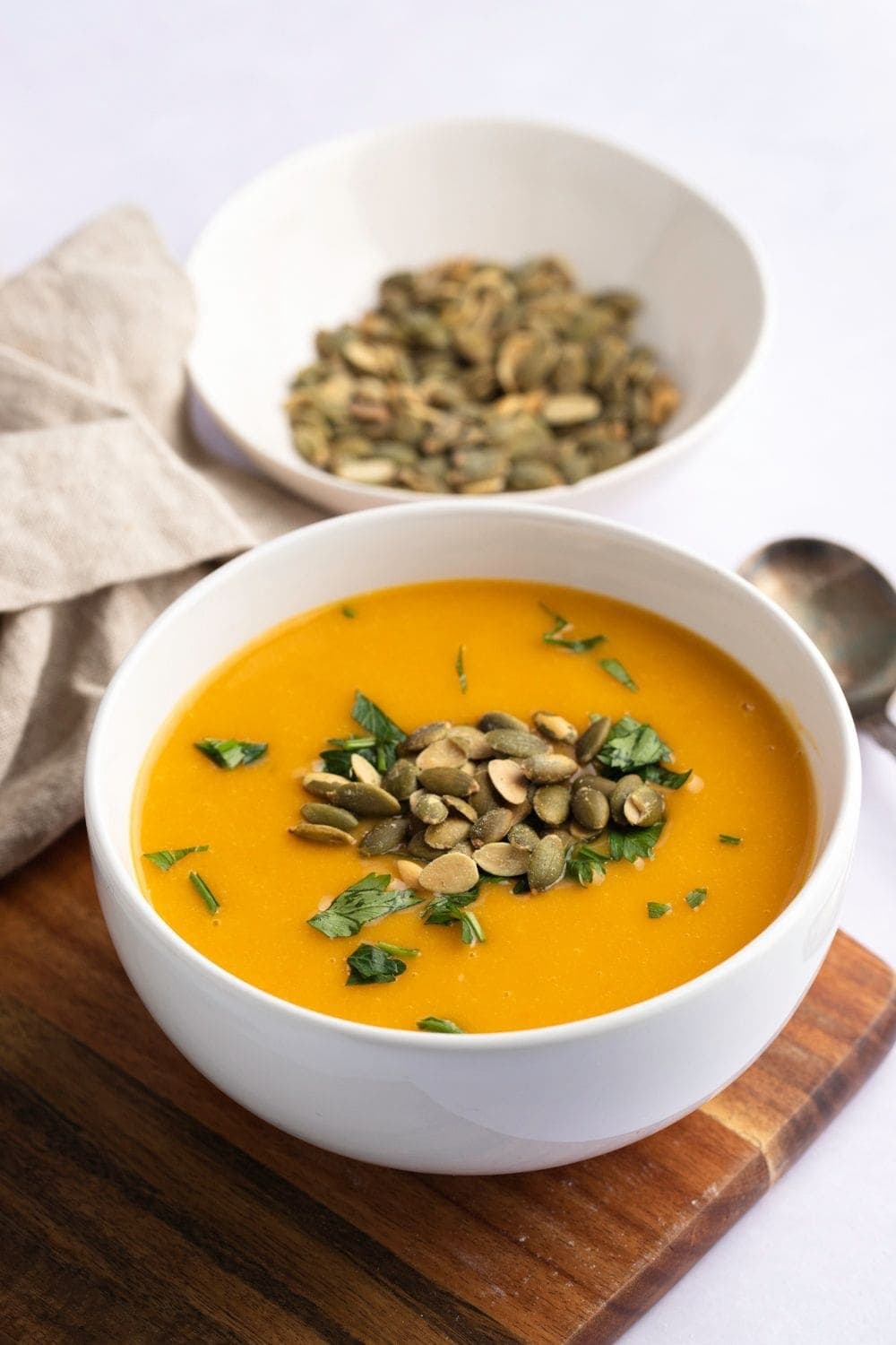 Homemade butternut squash topped with herbs and pumpkin seeds in a bowl