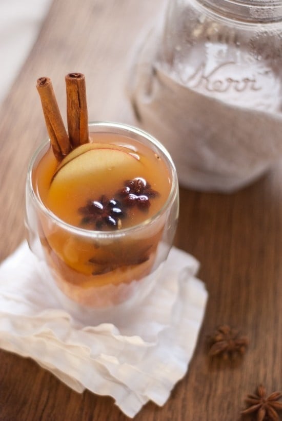 A glass of wassail with cinnamons sticks, star anise and orange slices garnish. 