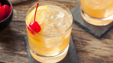 Two glasses of whiskey sour cockail with topped maraschino cherry