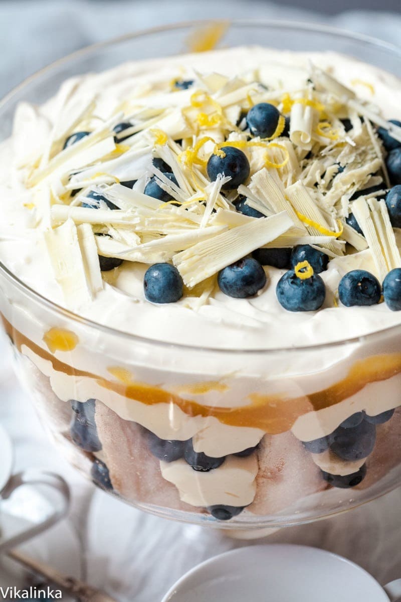 A delicious blueberry lemon trifle dessert with layers of cake, creamy filling, topped with fresh blueberries and chocolate shavings.
