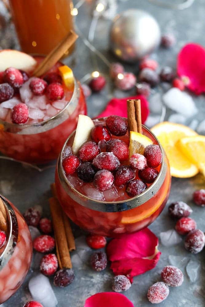 Sangria on a glass with ice and sugared cranberries, lemon slice and cinnamon stick garnish. 