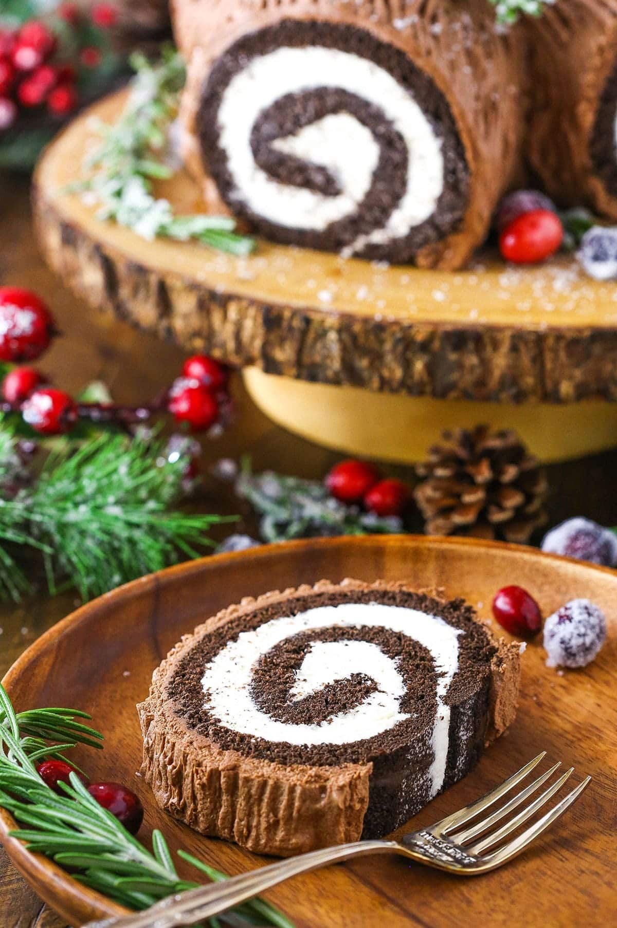 A slice of chocolate cake roll layered with cream and frosting served on a holiday table.