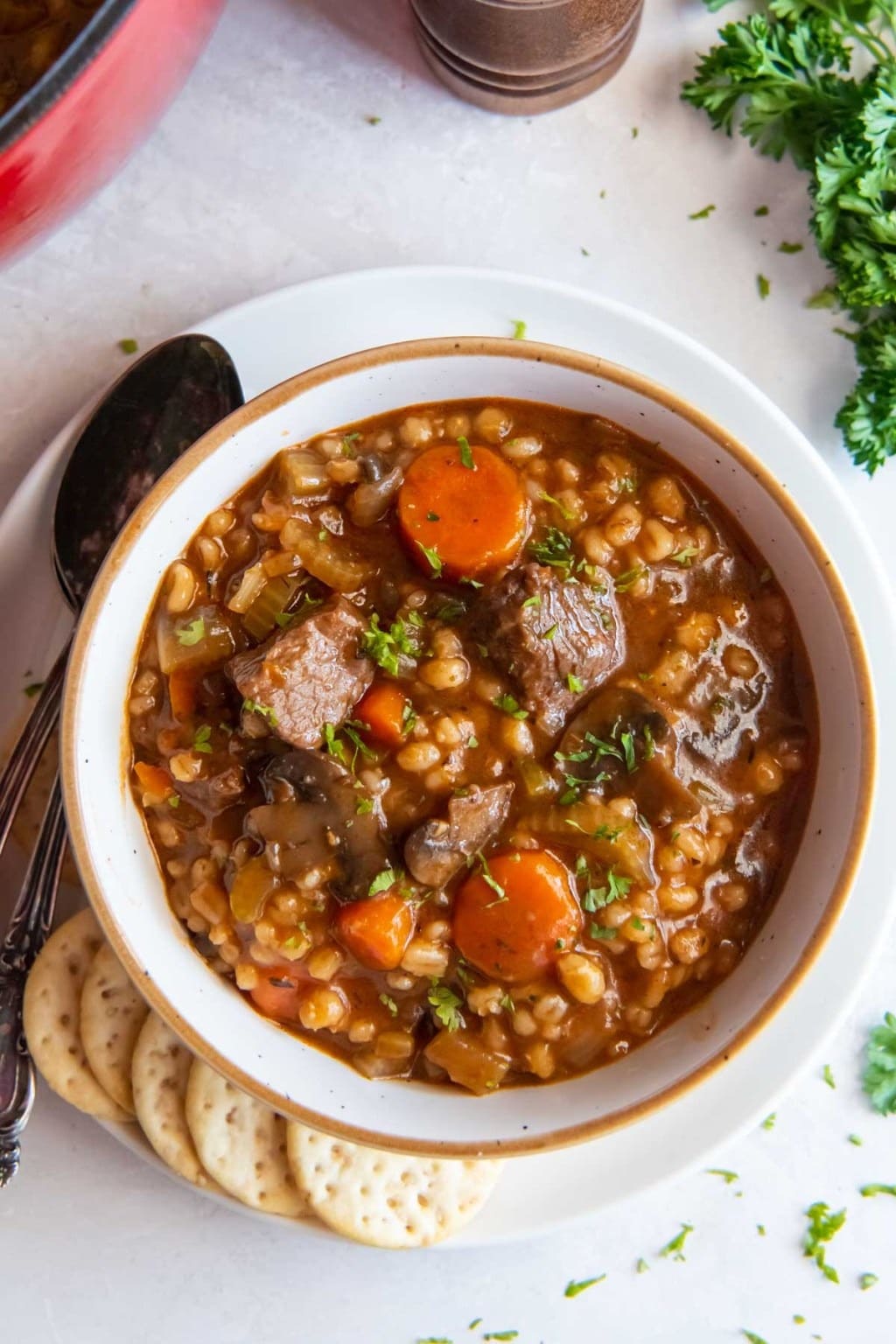 Warm beef barley soup with thick chuck roast and vegetables served with biscuits on the side