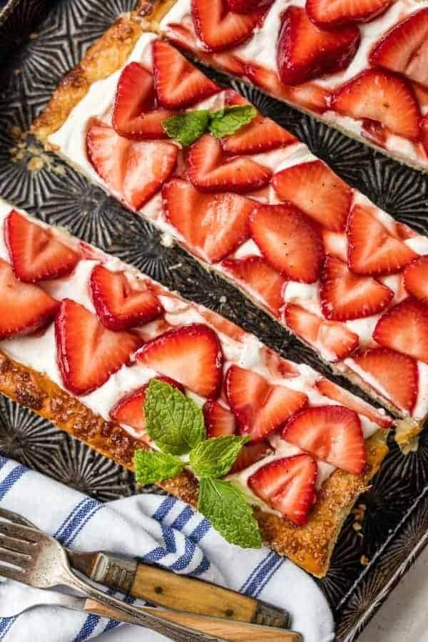 Pastry tarts topped with slices of strawberry and cream cheese.  