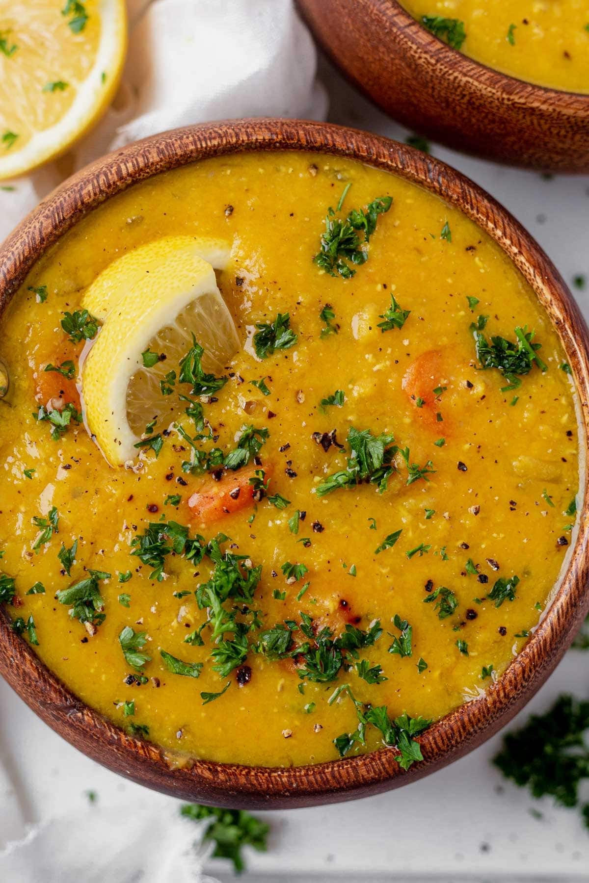Lemon lentil soup with tumeric and herbs in a bowl- close up, top view