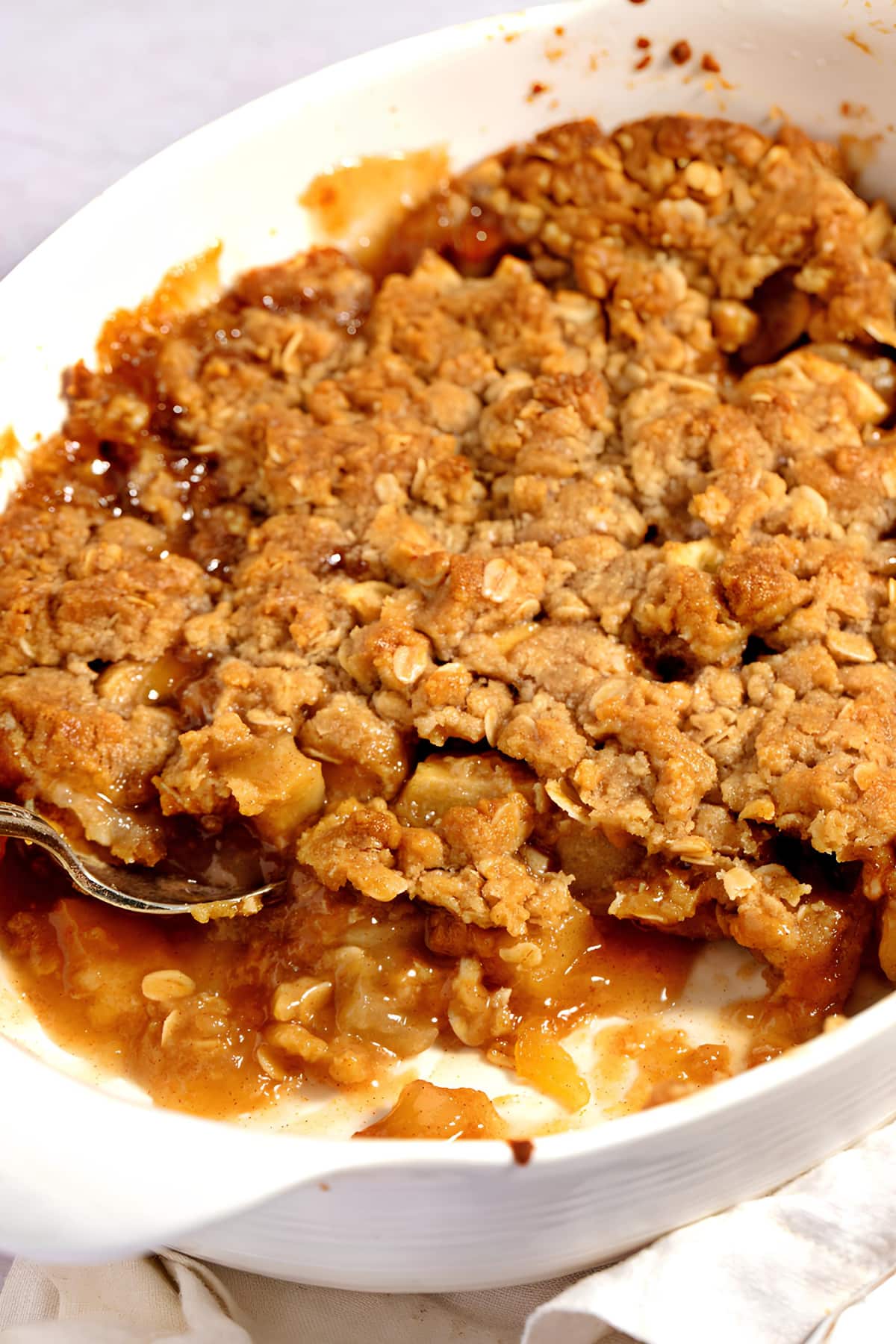 Apple crumble on a casserole dish with spoon.