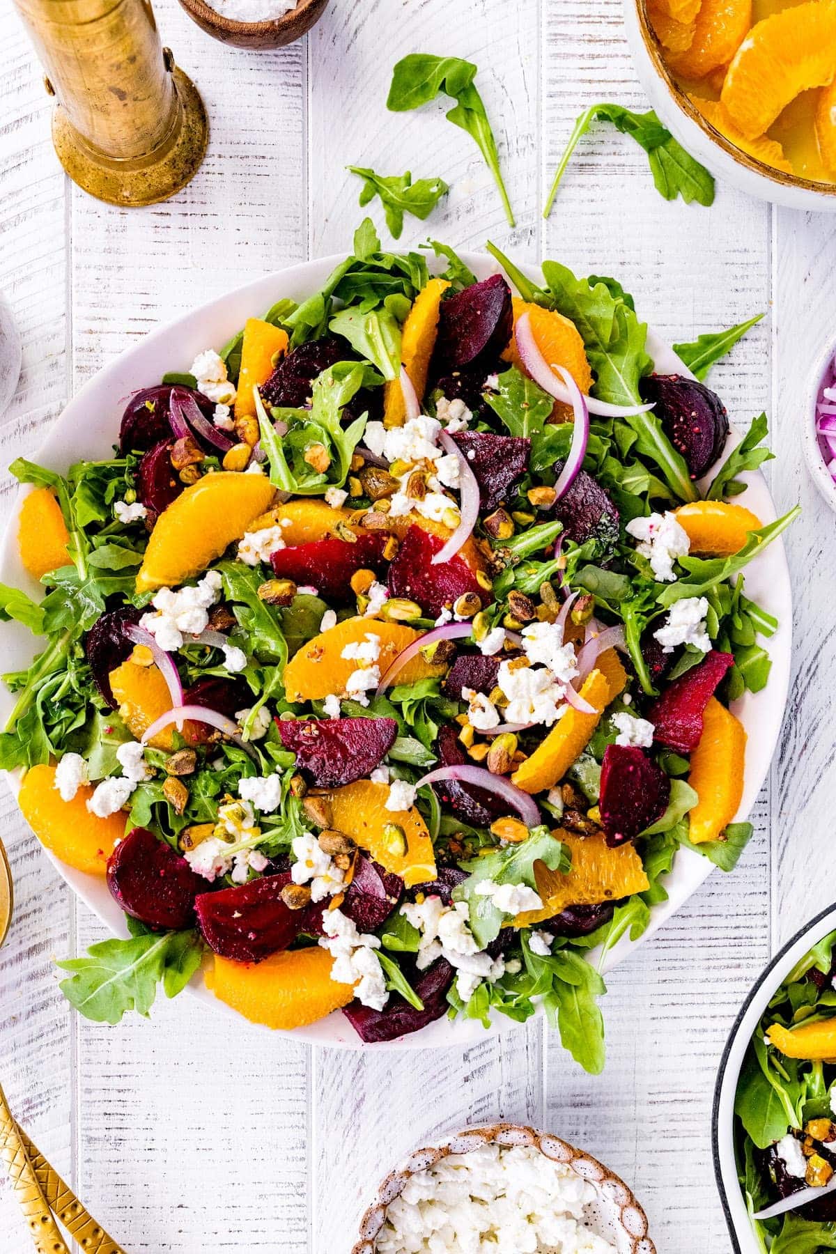 Salad on a bowl with mixed beets, peppery arugula, orange, and goat cheese.
