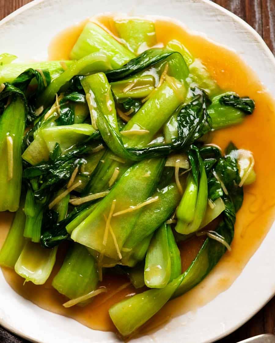 Bok choy soaked in ginger sauce served on a white plate.