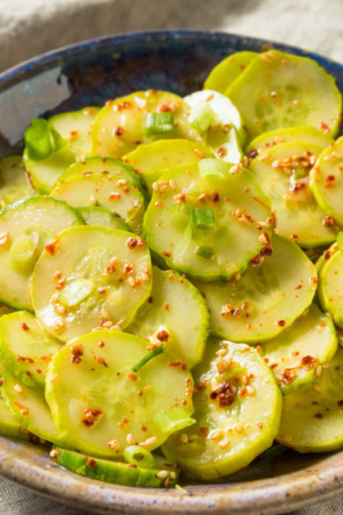 Asian cucumber salad on a bowl with chili flakes and scallions.