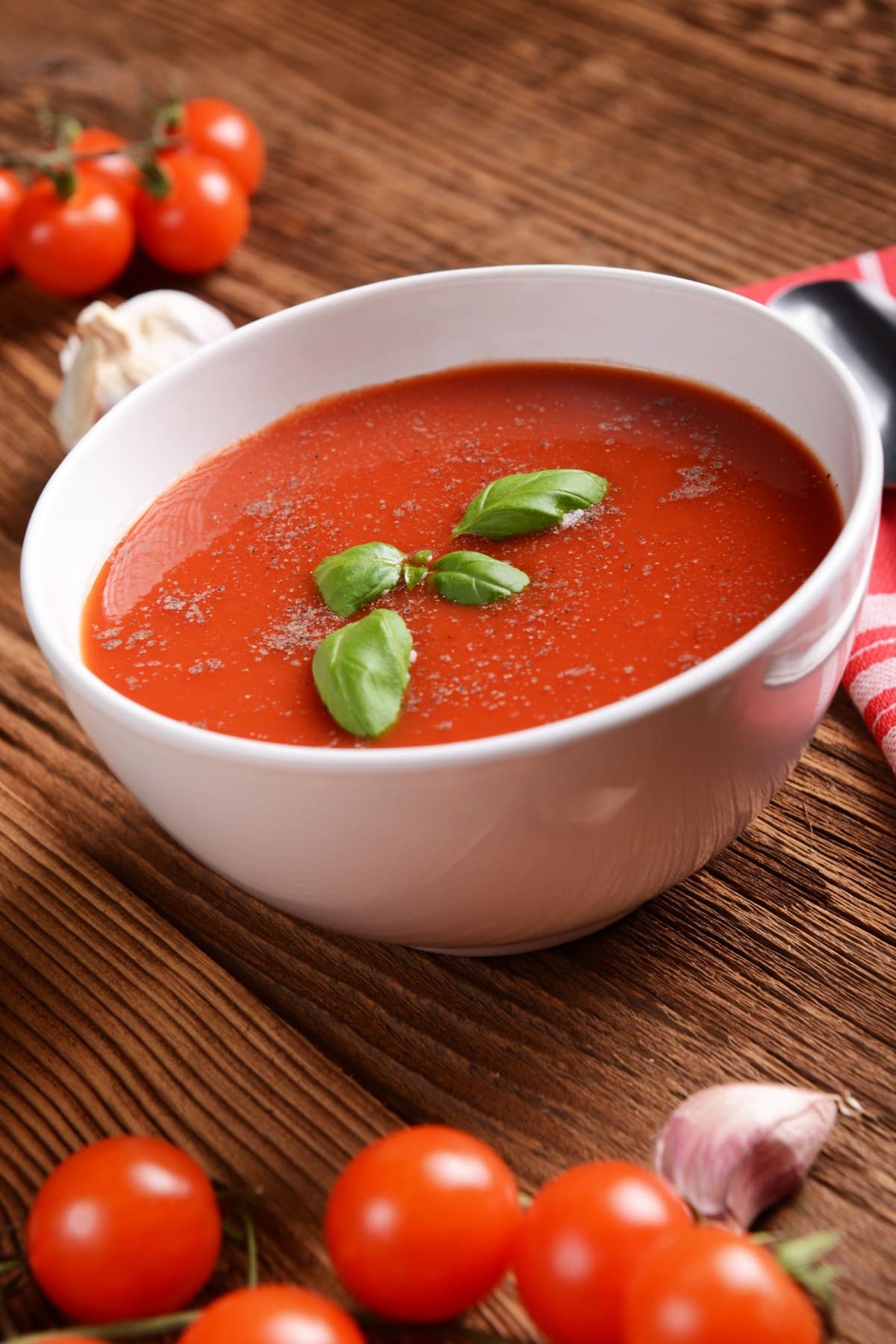 Homemade classic tomato soup with basil in a white bowl