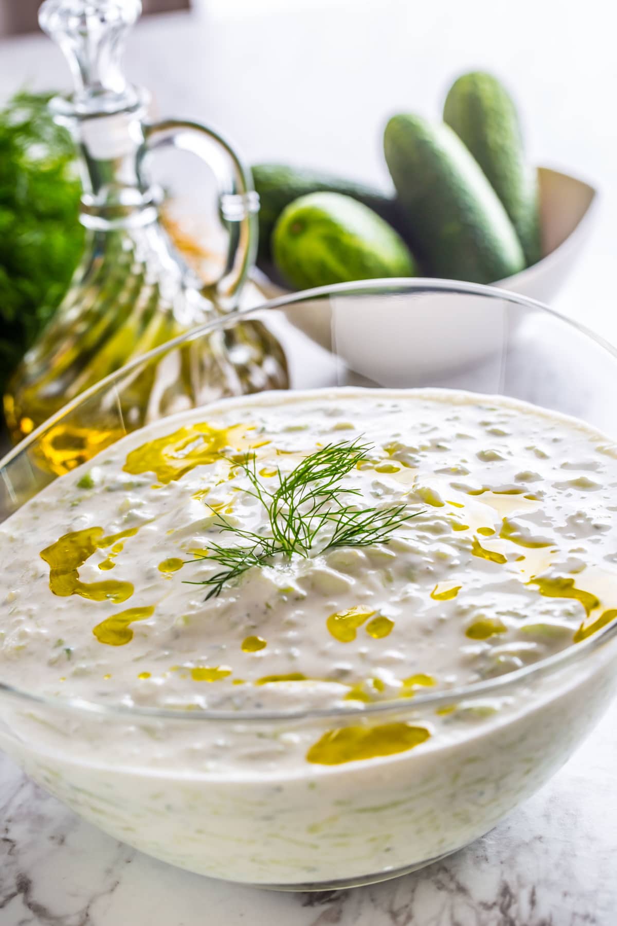 Tzatziki sauce in a glass bowl with a drizzle of olive oil.
