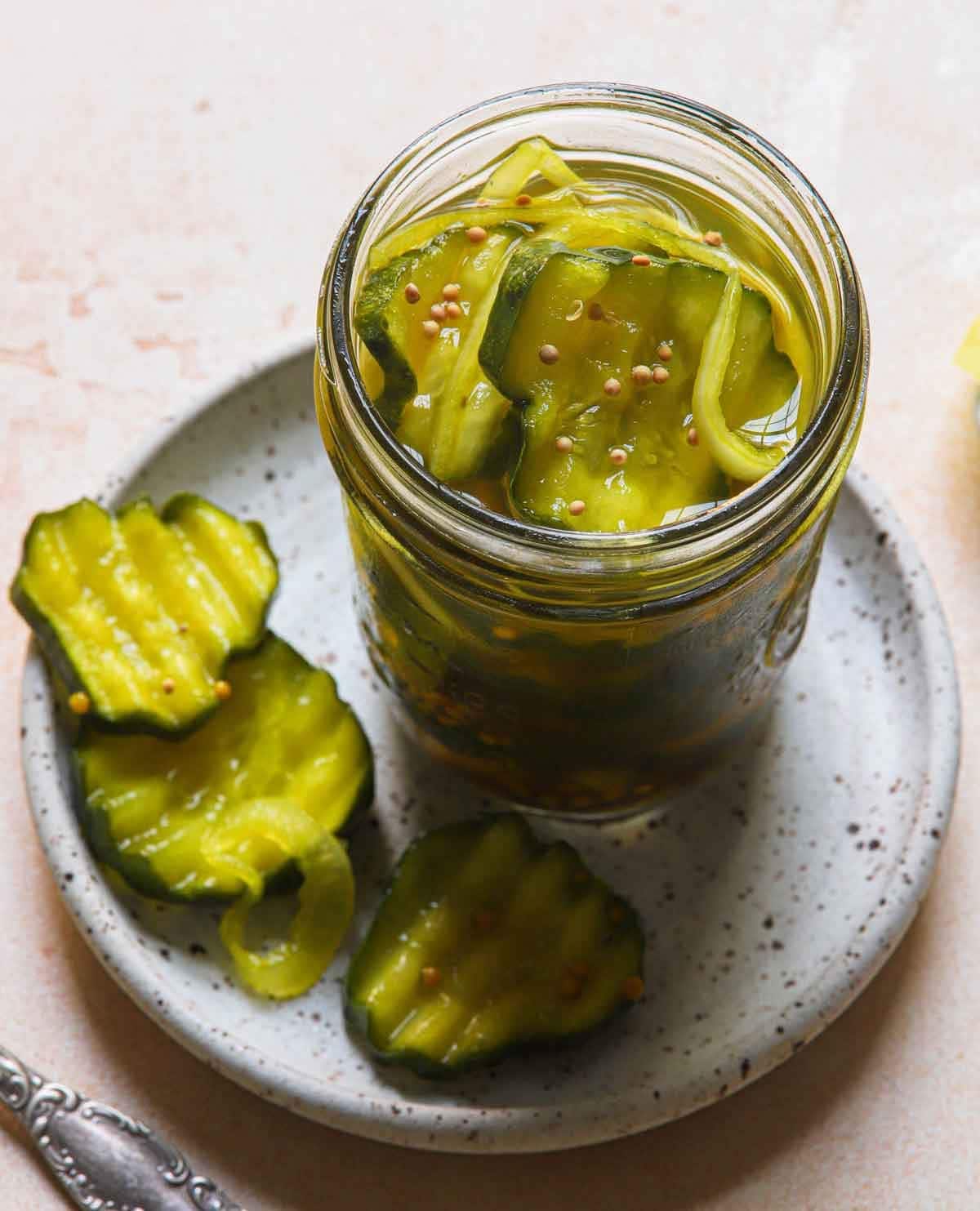 Sliced cucumber soaked in brine on a small glass jar.