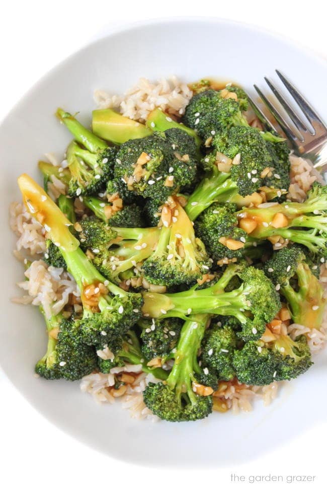 Broccoli with Asian-style garlic sauce topped on a white rice in a bowl.