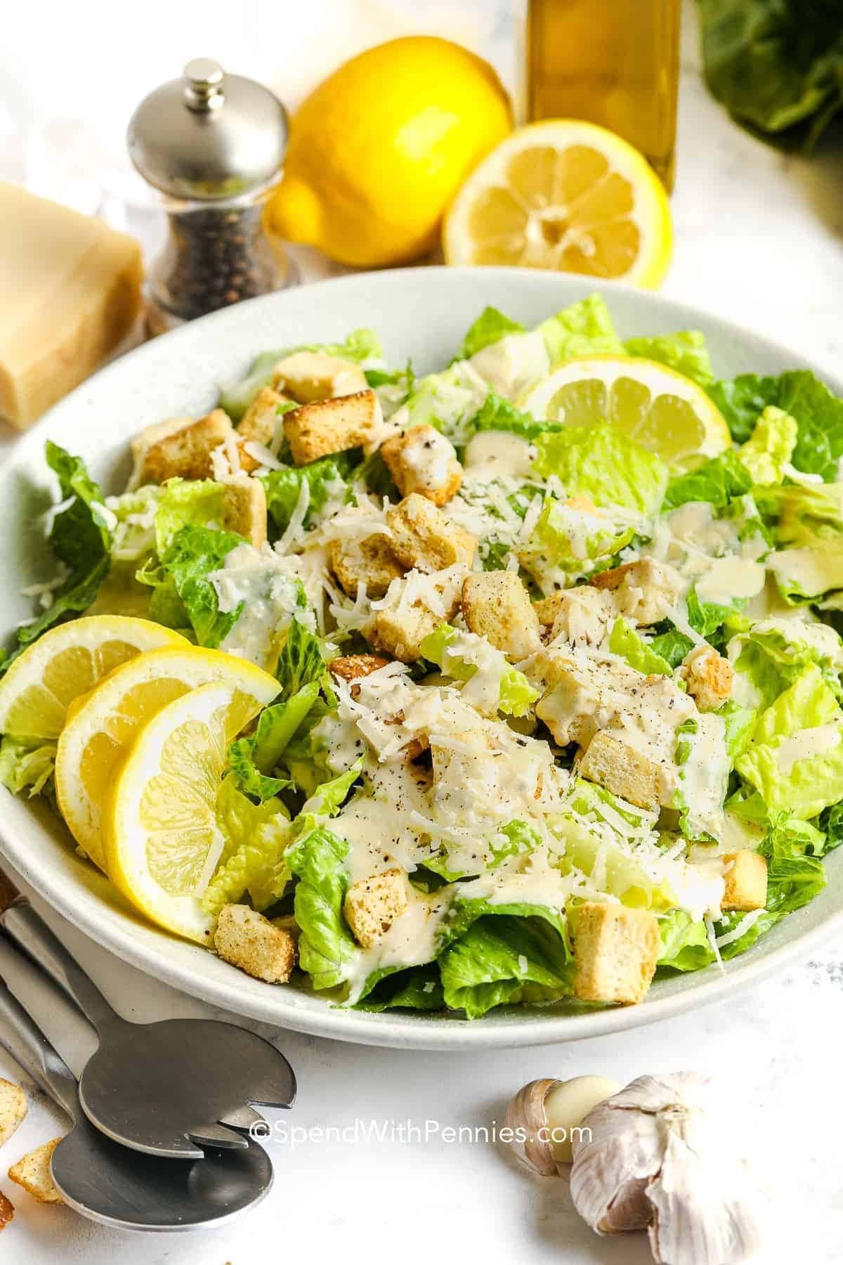 Caesar salad on a bowl with crunchy croutons and crisp greens garnished with lemon slices.