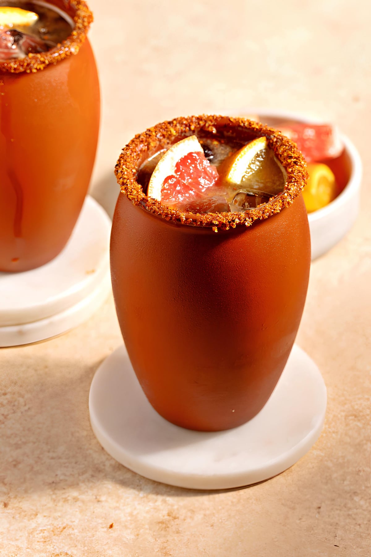 Cantarito Cocktail Recipe: served on a Cantarito clay dipped in tajin on rim garnished with sliced grapefruit.