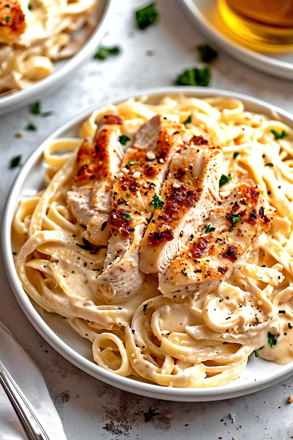 Creamy and cheesy chicken alfredo pasta with herbs in a white plate