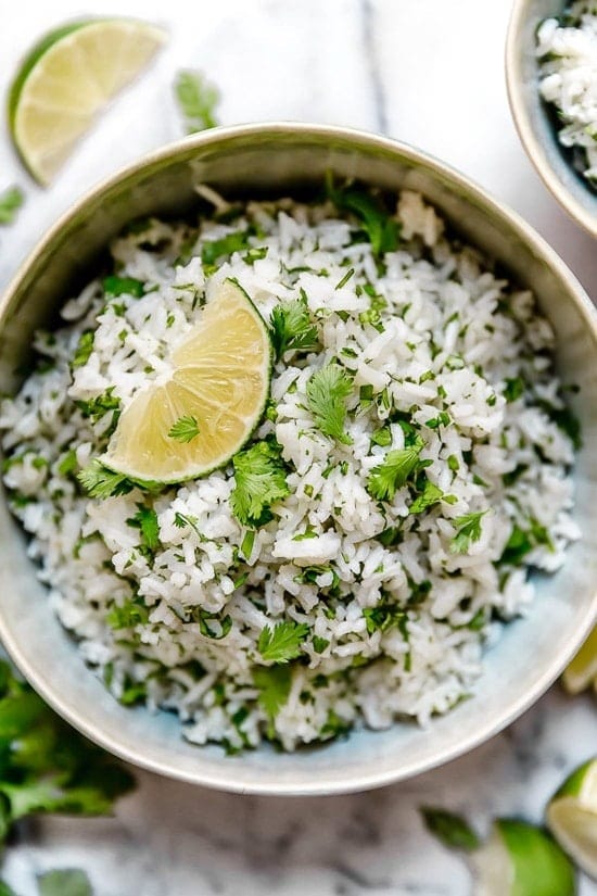 Cooked rice with cilantro and lime on a bowl.