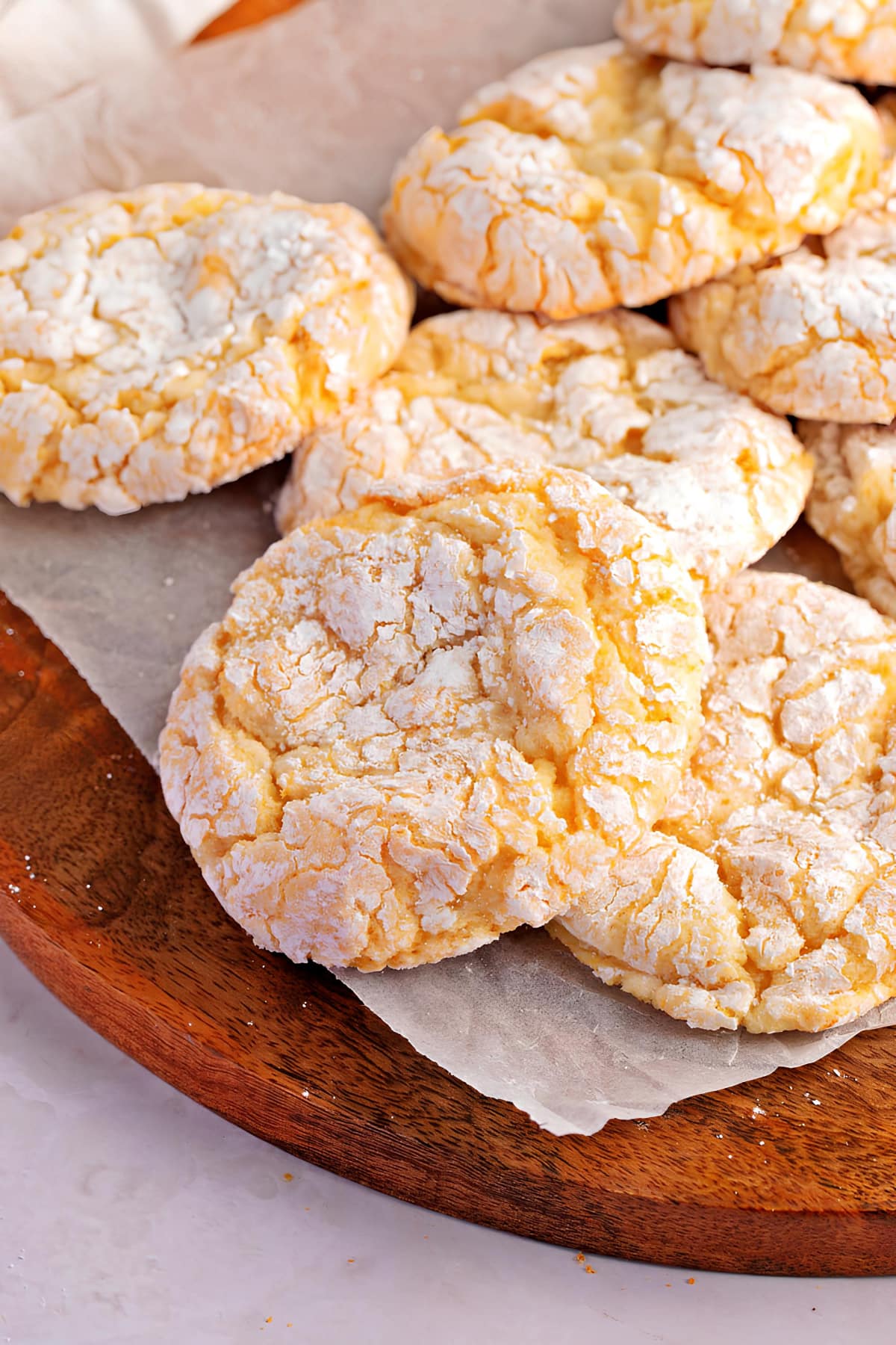 Bunch of crumbly cool whip cookies with powdered sugar coating on a wooden board. 