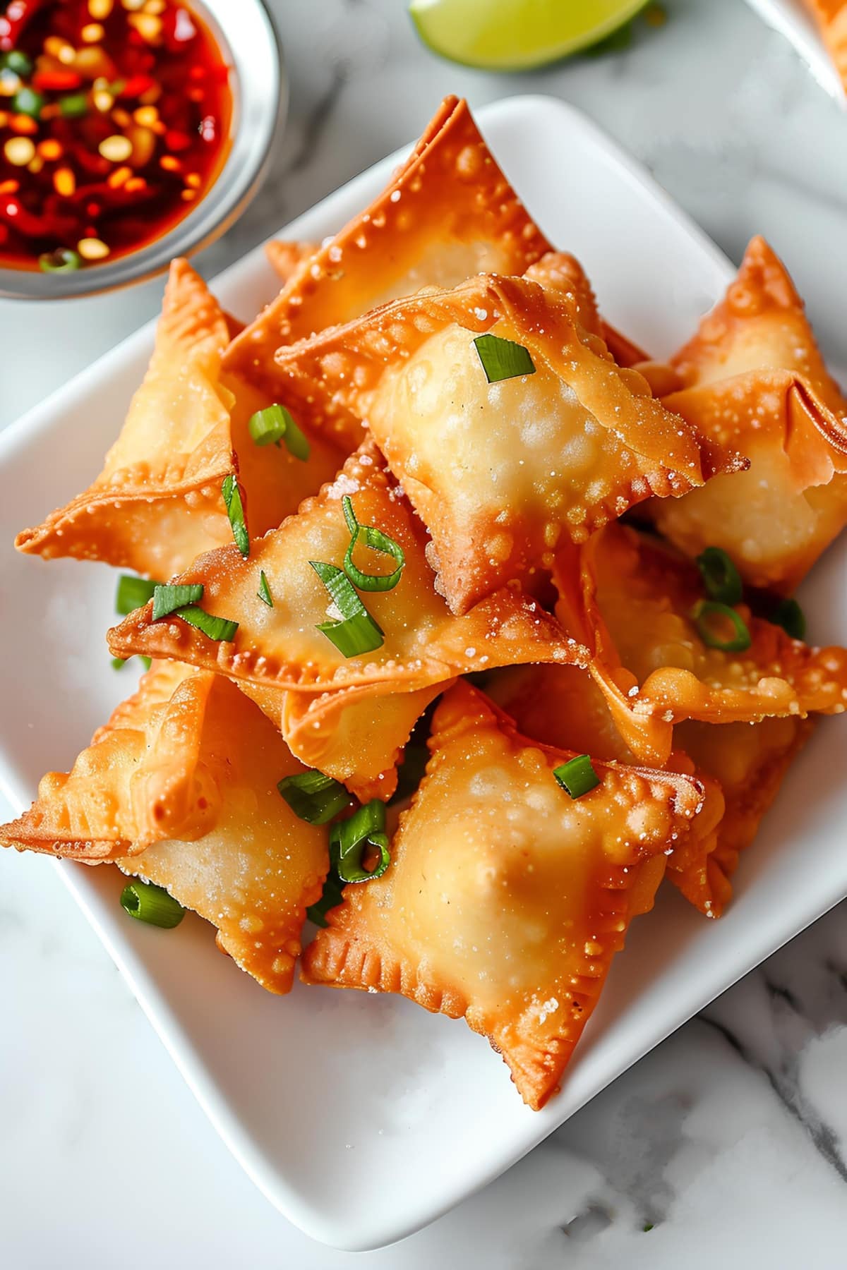 Crab rangoon with chili sauce topped with green onions