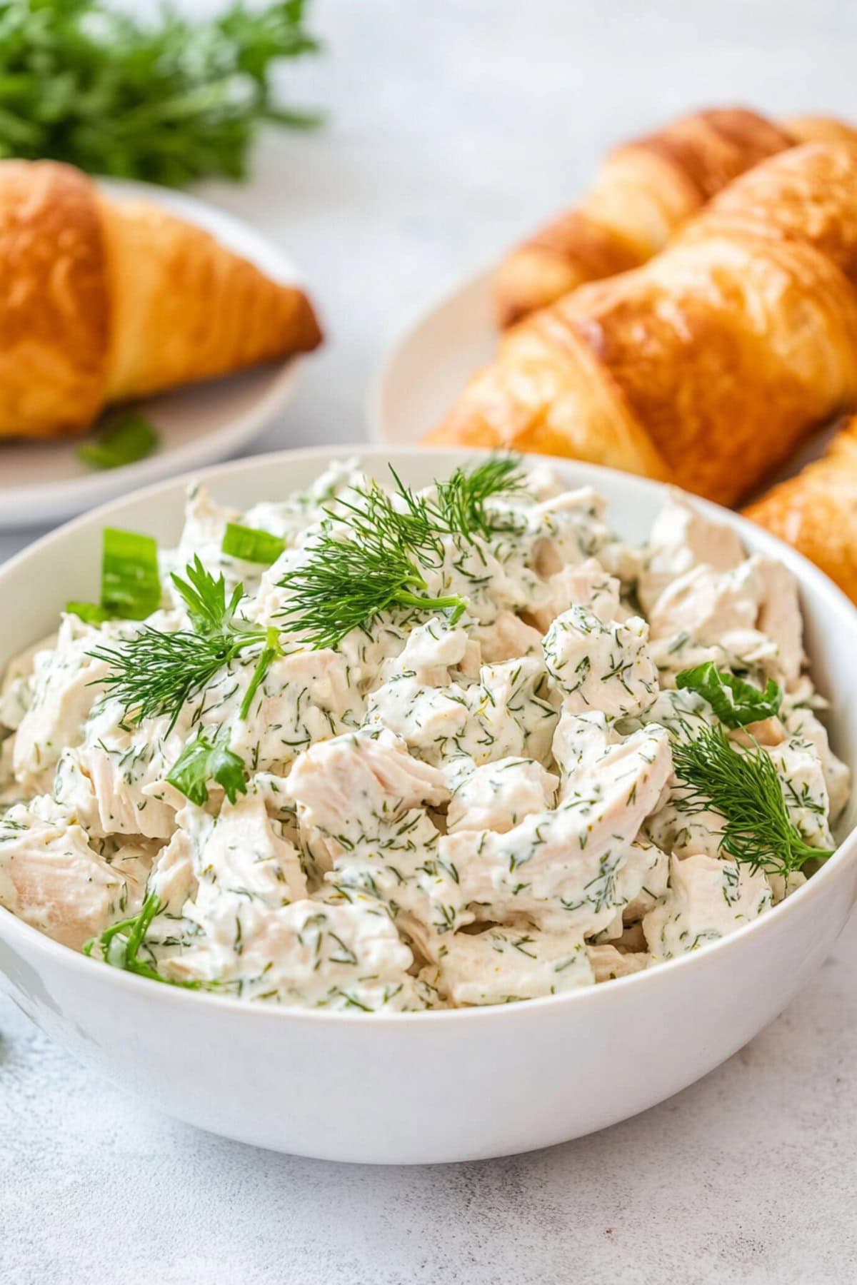 Dill Chicken Salad in a white bowl with croissants