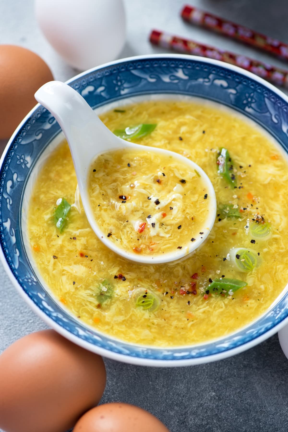 Egg Drop Soup (Easy 15-Minute Recipe): Egg drop soup served in a Chinese bowl with soup spoon. 
