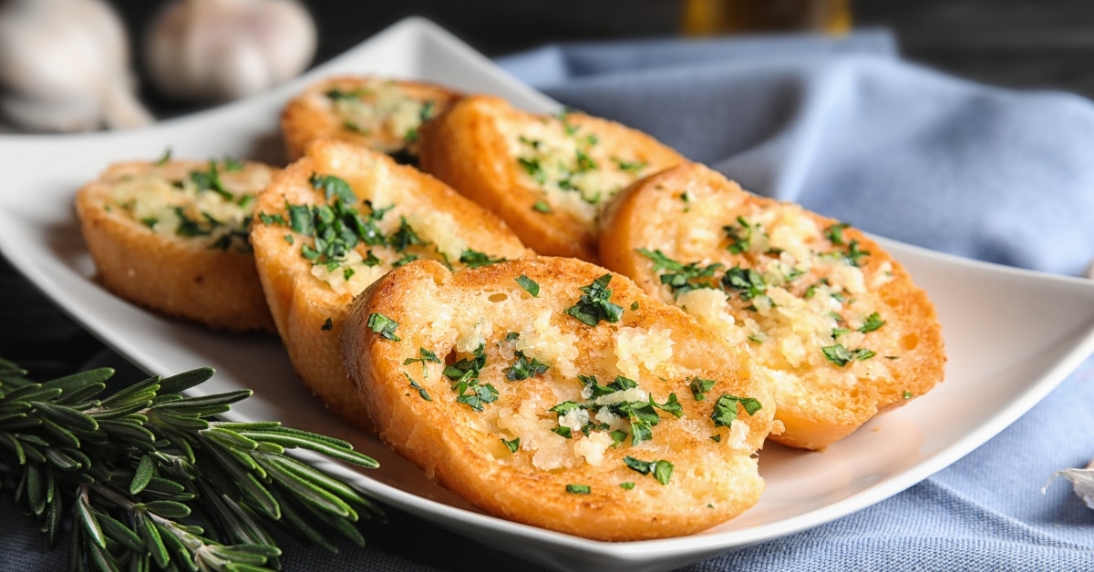 A deliciously golden garlic bread topped with fragrant herbs on a plate