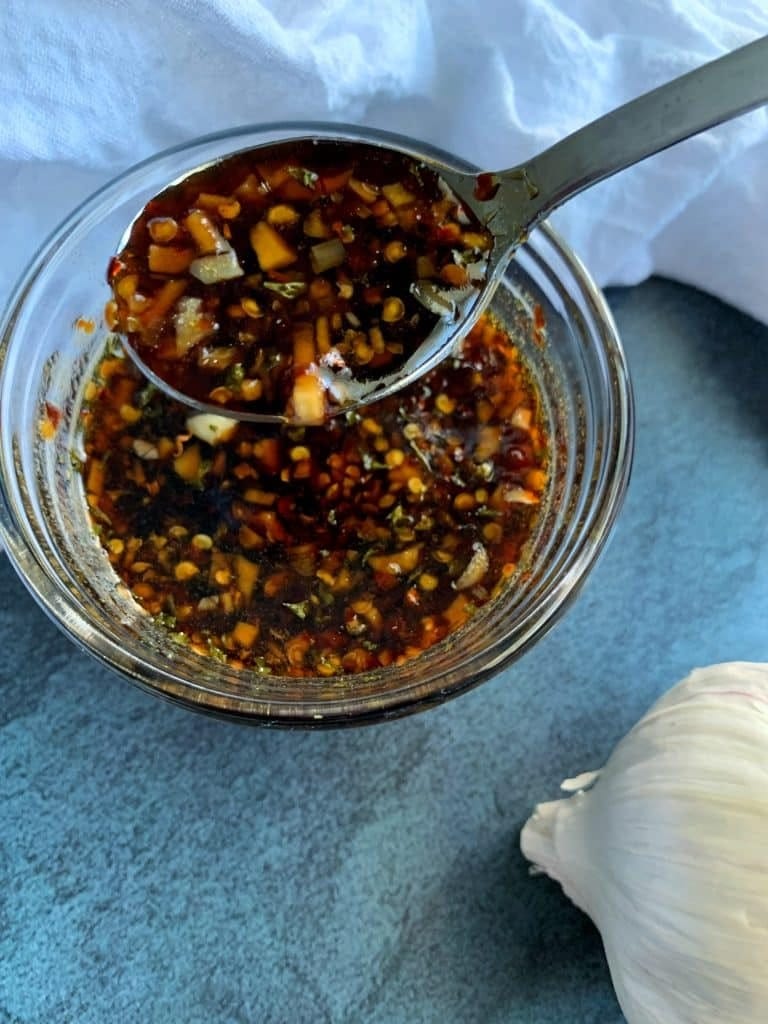 Spoon mixing garlic honey soy sauce in a jar. 