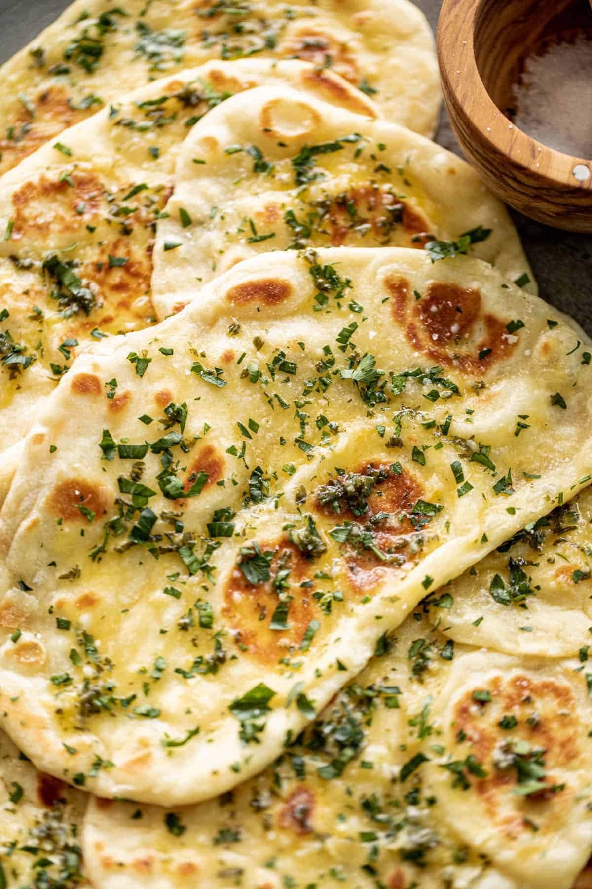 Garlic naan bead with garlic butter spread on top sprinkled with chopped herbs. 