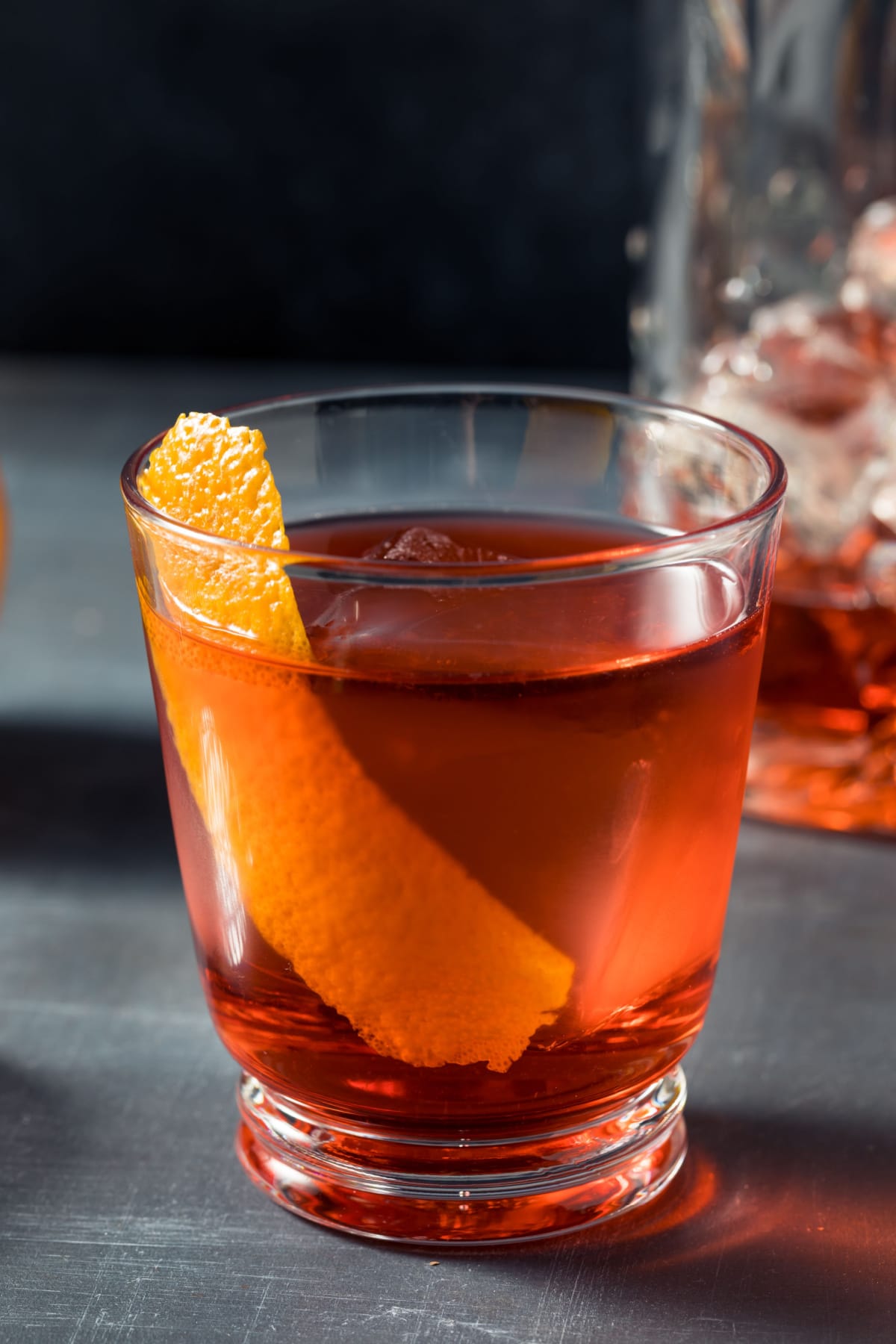A glass of Mezcal Negroni cocktail garnished with lemon peel.