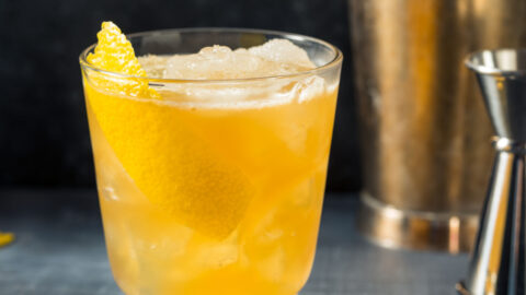 Ice filled glass filled with gold rush cocktail.