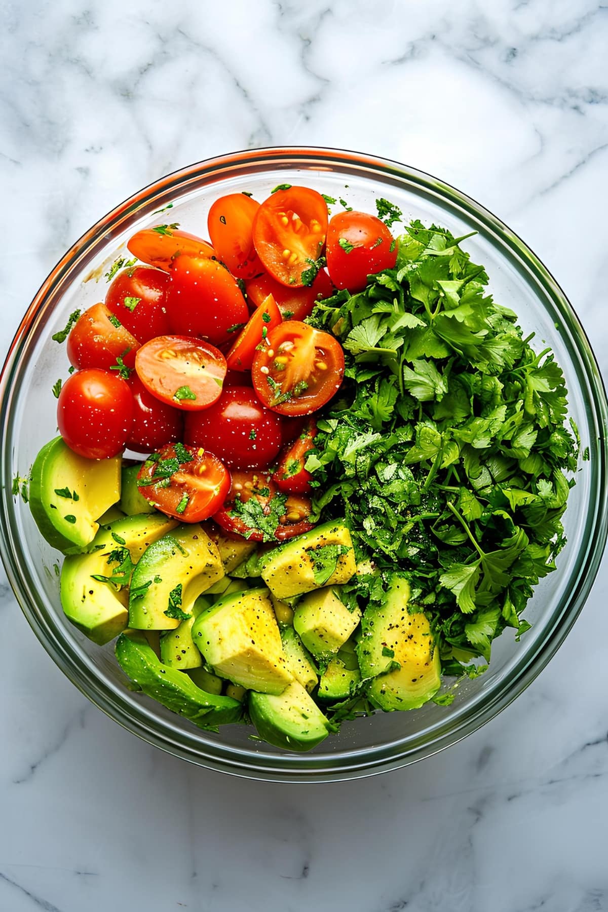 Fresh avocados, tomatoes and cilantro in a glass bowl