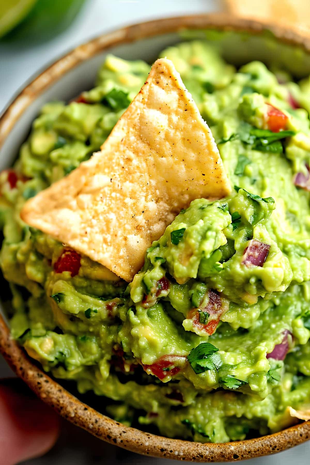 A bowl of guacamole with tortilla chips, perfect for dipping, top view