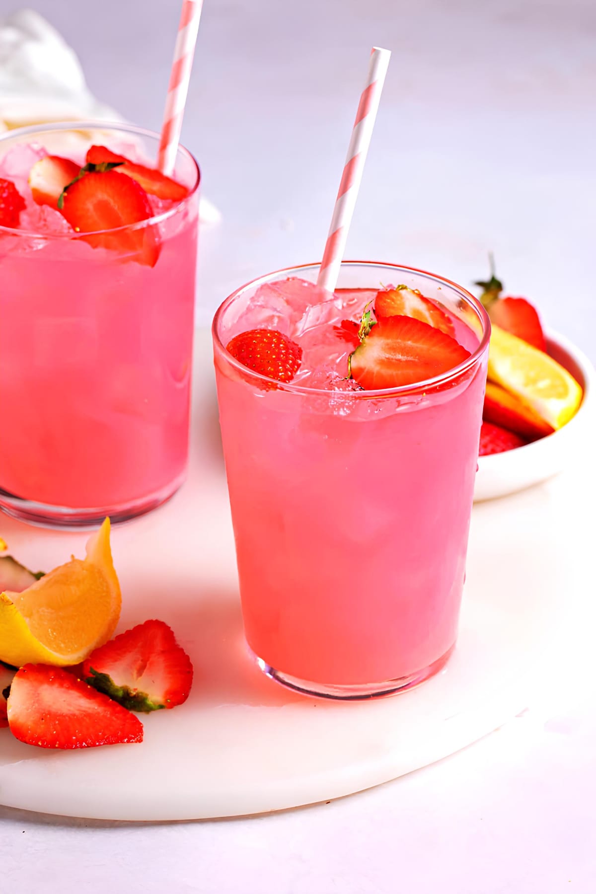 Two glasses of hippie juice garnished with slices of strawberries.