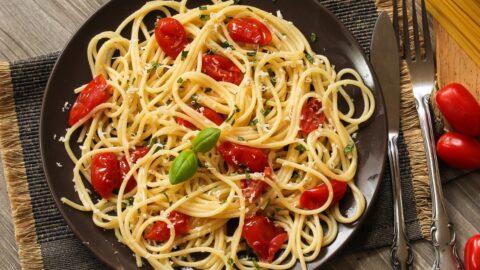 Italian pasta dish with vibrant red tomatoes and fresh basil leaves, a classic combination bursting with flavor.