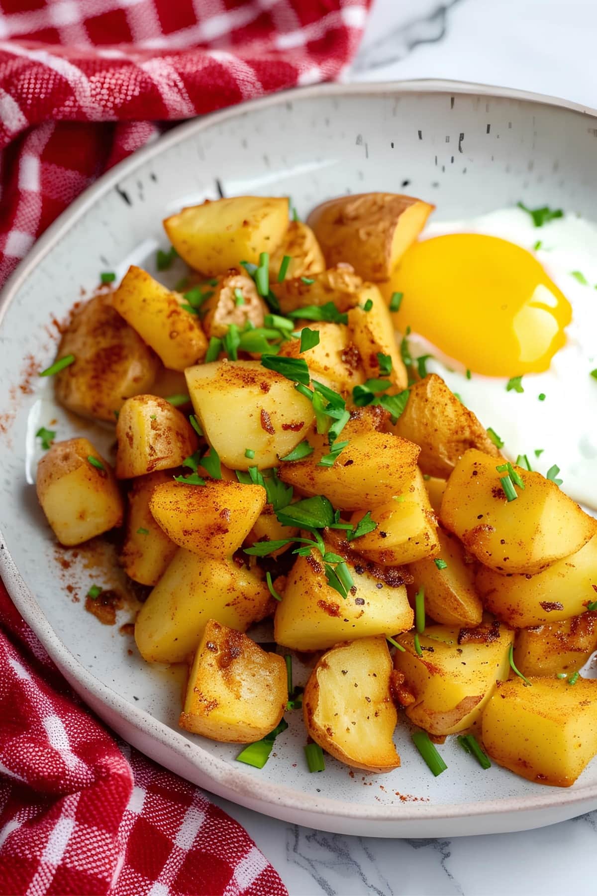 Fried potatoes with a sunny-side-up egg on a plate, a delicious and hearty breakfast dish