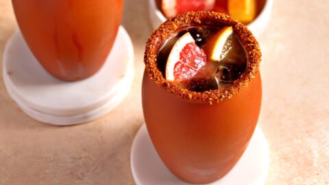 Cocktails on cantarito mugs rims dipped on tajin garnished with sliced grapefruit.