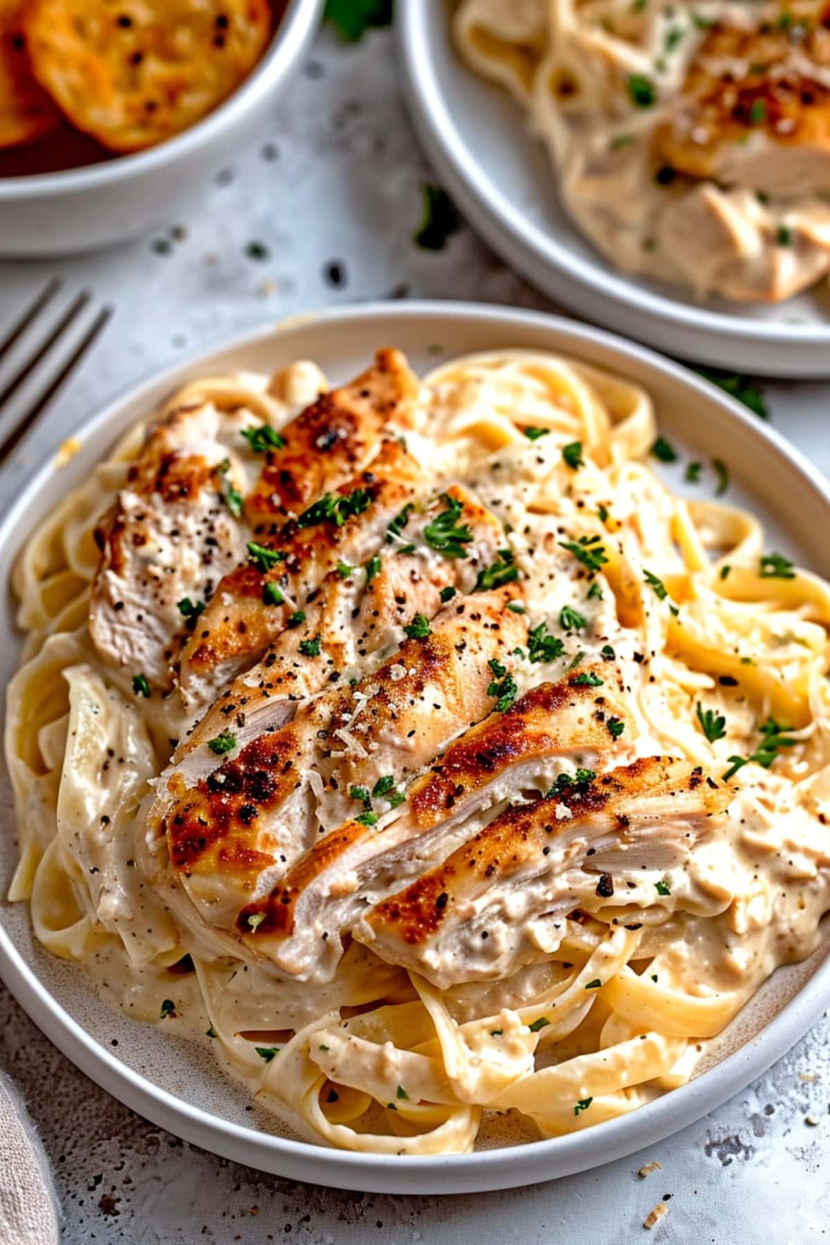 Creamy chicken alfredo pasta with herbs in a white plate