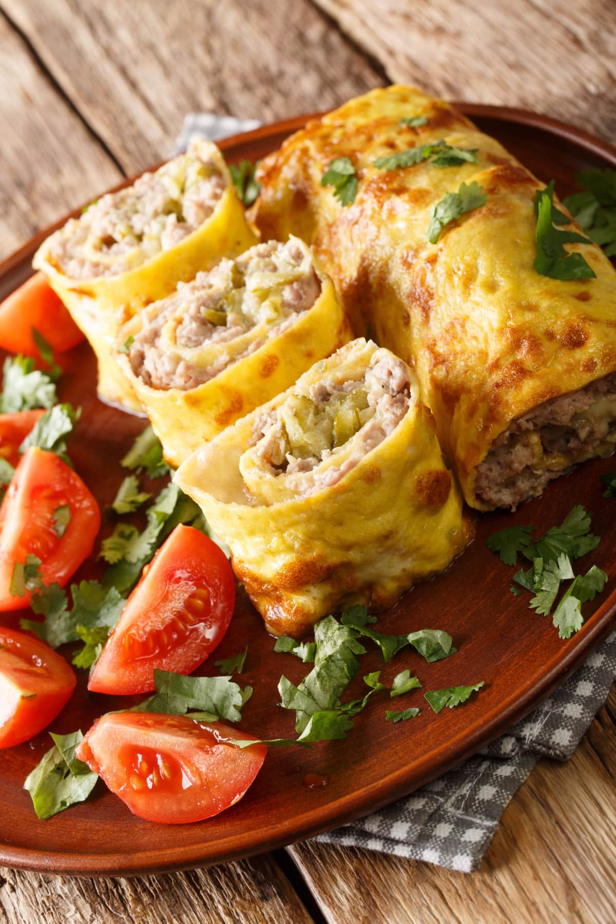 Egg rolls filled with ground meat served with tomatoes and cilantro on a wooden table