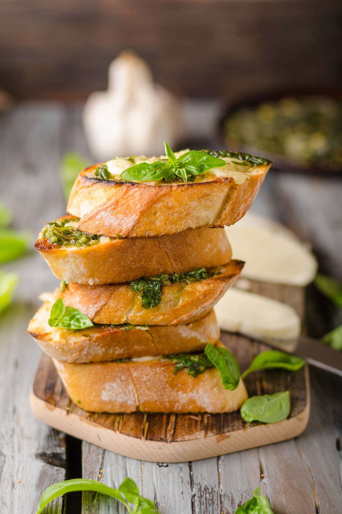 A Stack of Garlic Bread with Cheese and Basil on a Wooden Board