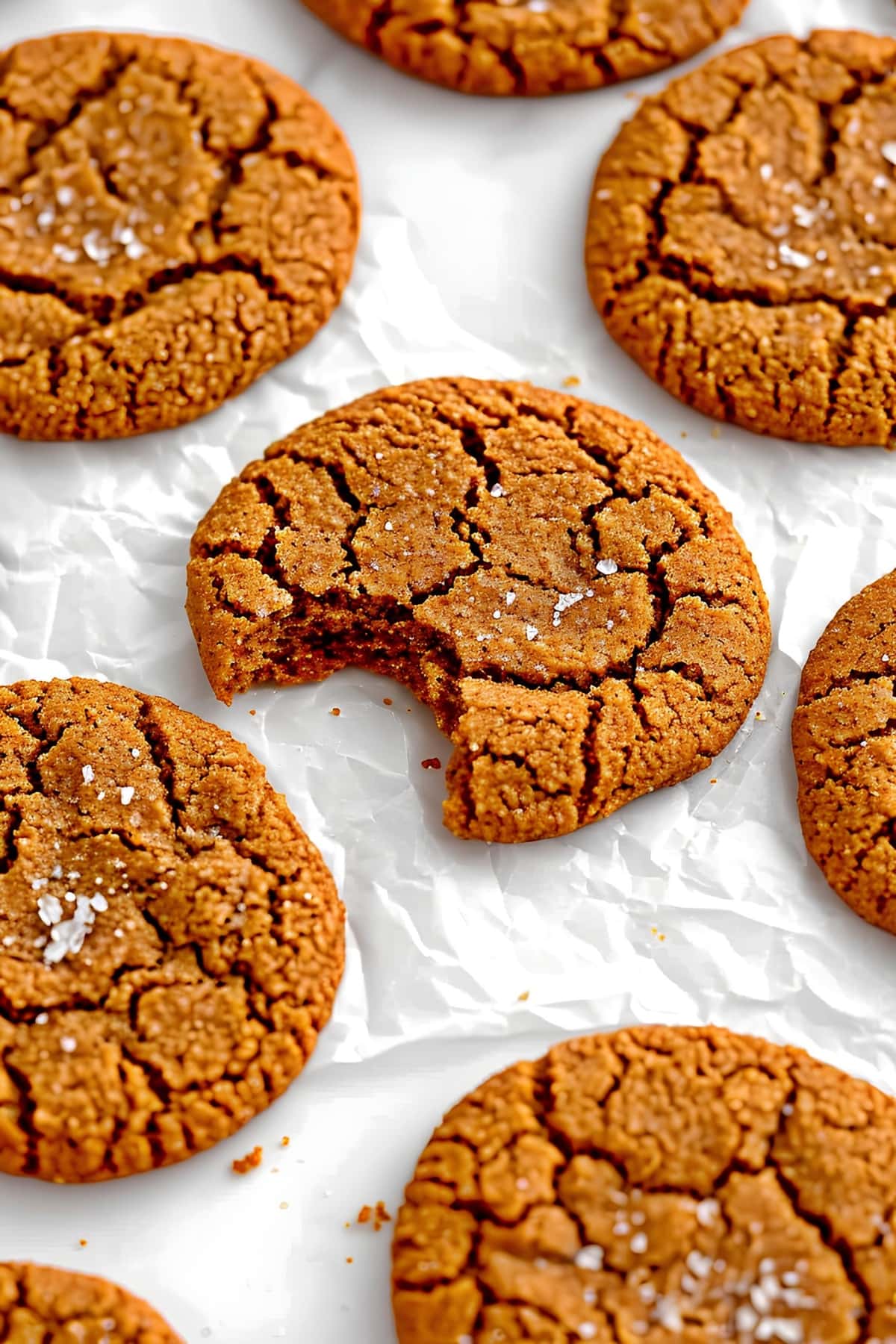 Soft and chewy ginger cookies on a white parchment paper topped with sugar