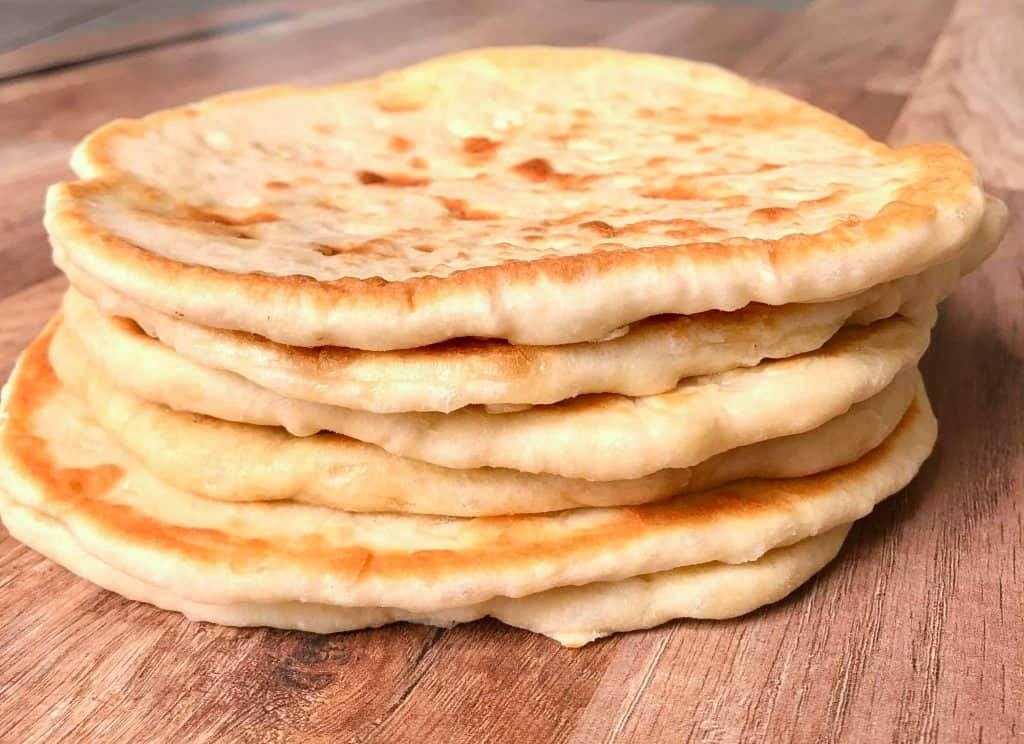 Stack of pita bread on a wooden table. 