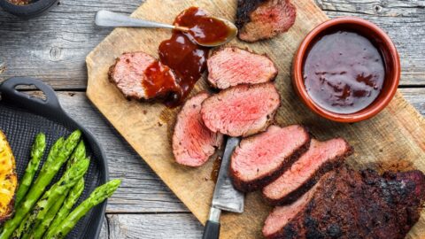 Barbecue dry aged wagyu tri tip steak with grilled pineapples and green asparagus on a wooden background