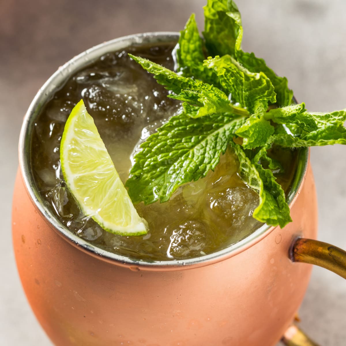 Kentucky mule mug filled with ice garnish with fresh mint sprig and lime slice.