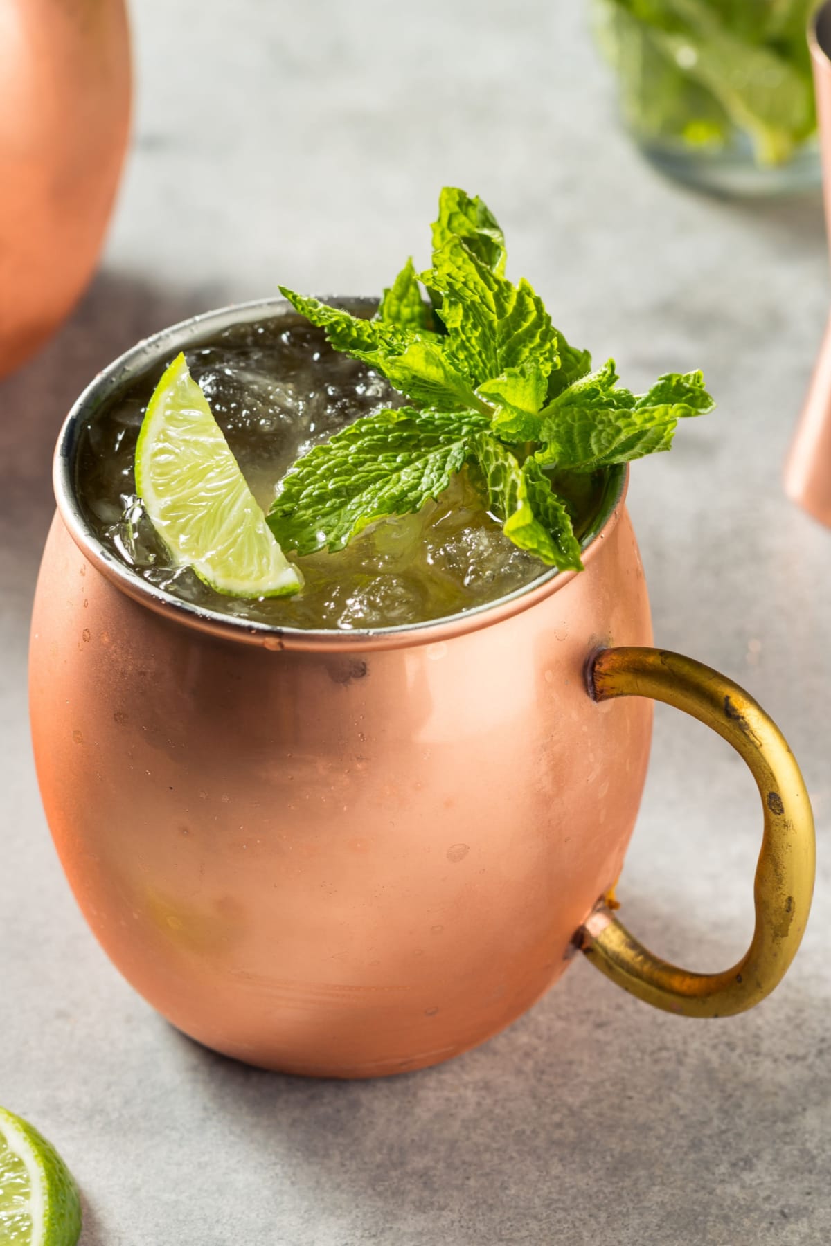Kentucky mule served in a mule mug filled with ice garnished with lime slice and fresh mint sprig.