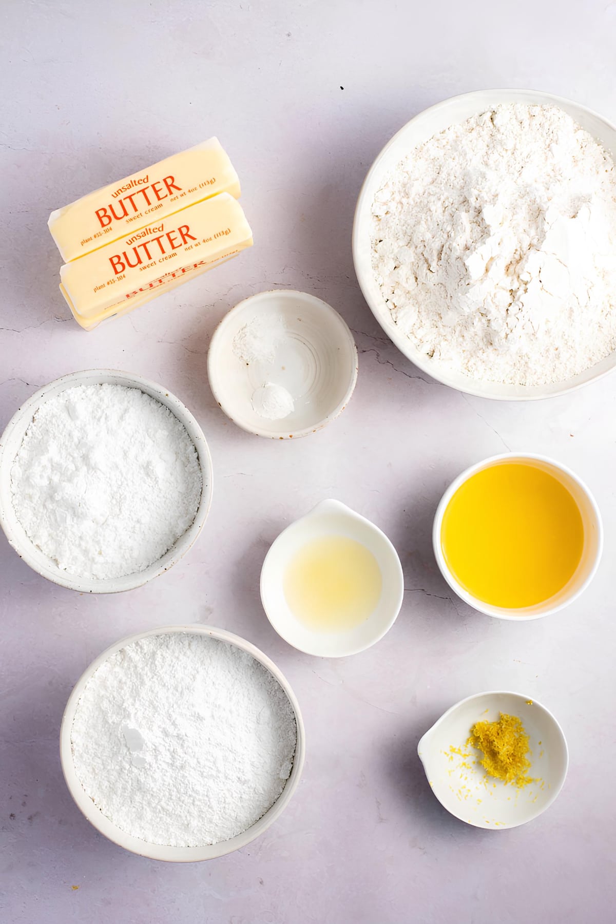 Lemon Shortbread Cookies Ingredient: flour, blocks of butter, eggs, and lemon juice portion on a white table surface. 