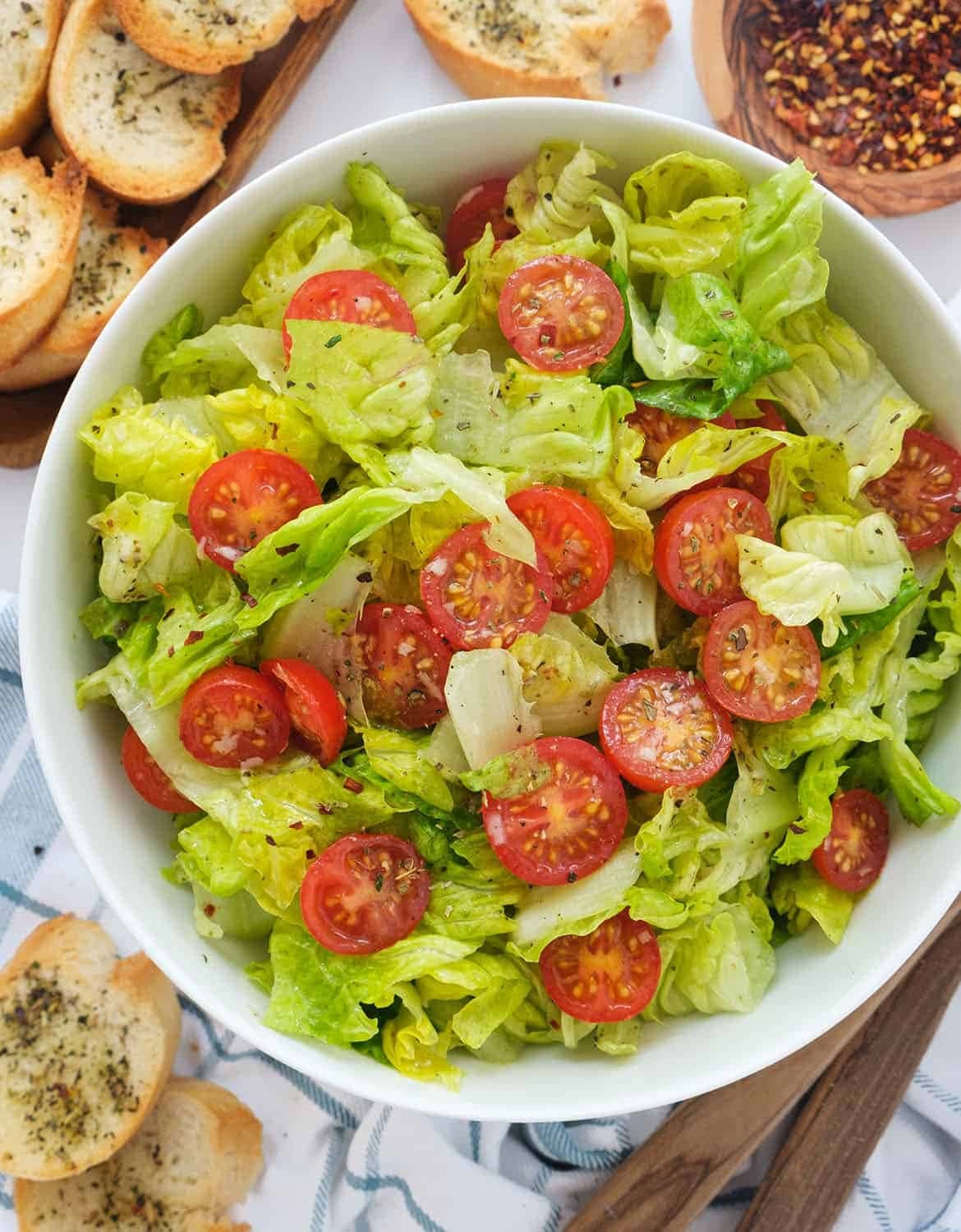 Lettuce salad with sliced cherry tomatoes on a white bowl. 