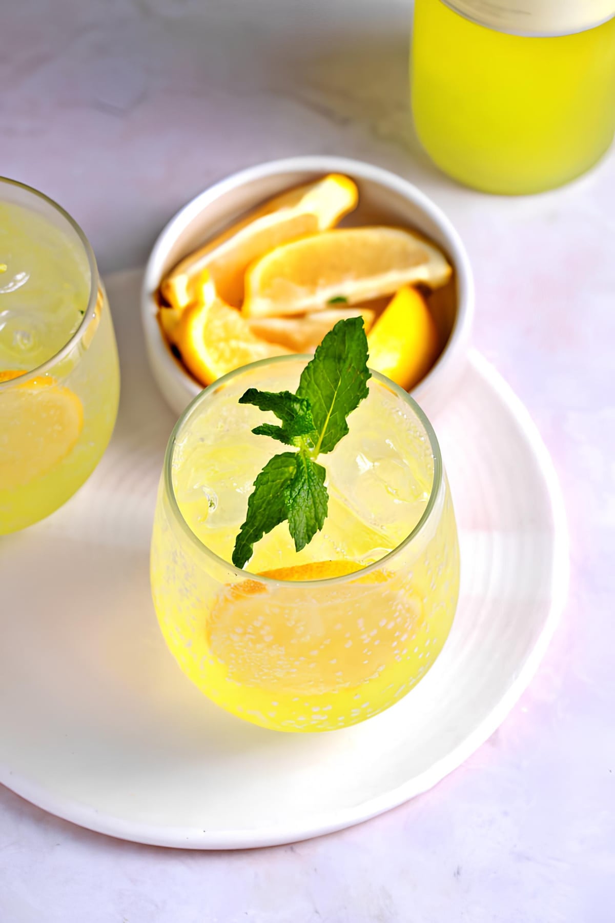 Top view of Limoncello spritz cocktail on glasses, garnished with lemon slices and fresh mint leaves. 